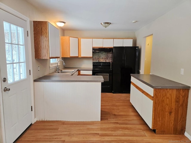 kitchen with light wood-type flooring, a healthy amount of sunlight, sink, black appliances, and white cabinets