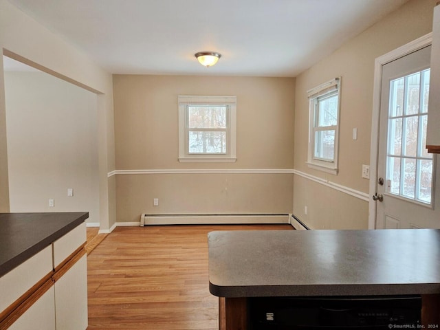 unfurnished dining area featuring baseboard heating, a healthy amount of sunlight, and light wood-type flooring