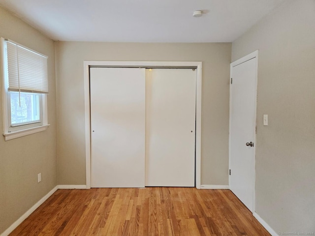 unfurnished bedroom with light wood-type flooring and a closet