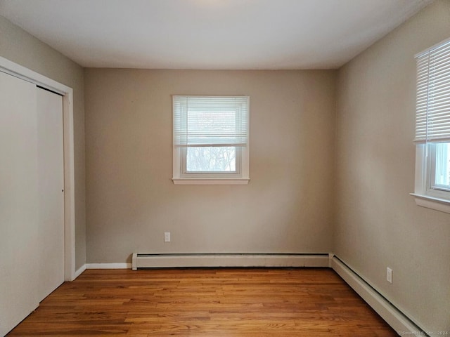 interior space with light wood-type flooring, a closet, and baseboard heating