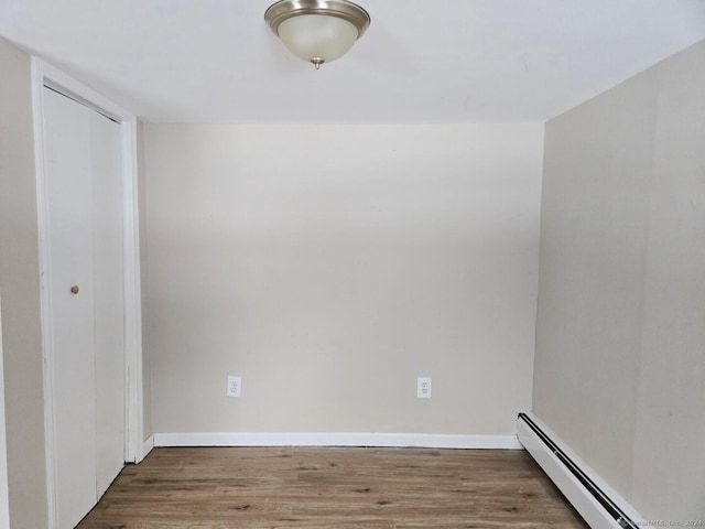 unfurnished room featuring a baseboard radiator and dark hardwood / wood-style floors