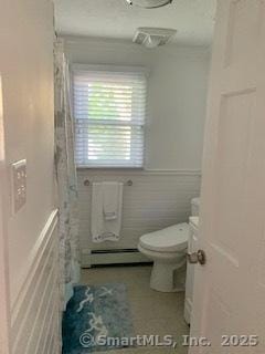 bathroom featuring baseboard heating, tile walls, and toilet