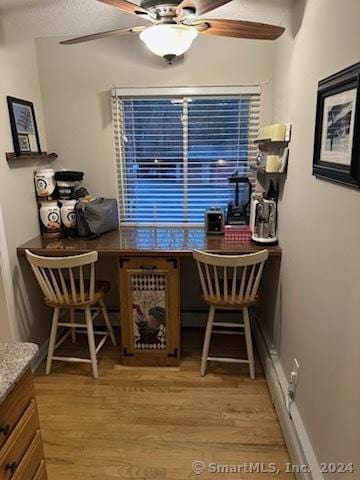 dining space with ceiling fan, built in desk, and light wood-type flooring