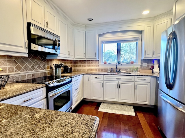 kitchen featuring light stone countertops, appliances with stainless steel finishes, dark wood-type flooring, sink, and white cabinetry