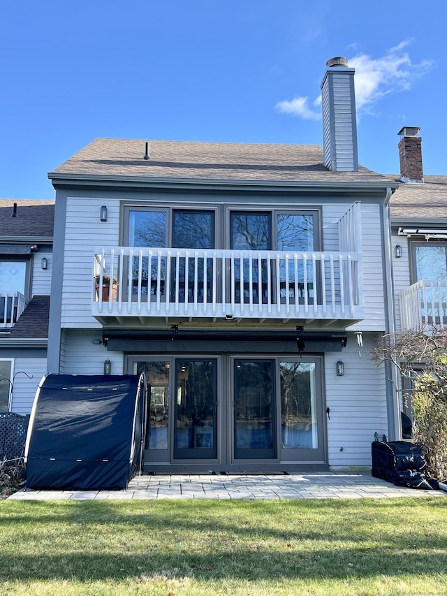 rear view of house with a yard and a balcony