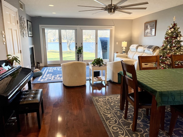 living room with ceiling fan, dark hardwood / wood-style flooring, and a water view