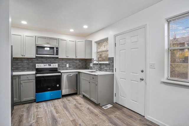 kitchen featuring gray cabinets, light hardwood / wood-style flooring, and appliances with stainless steel finishes