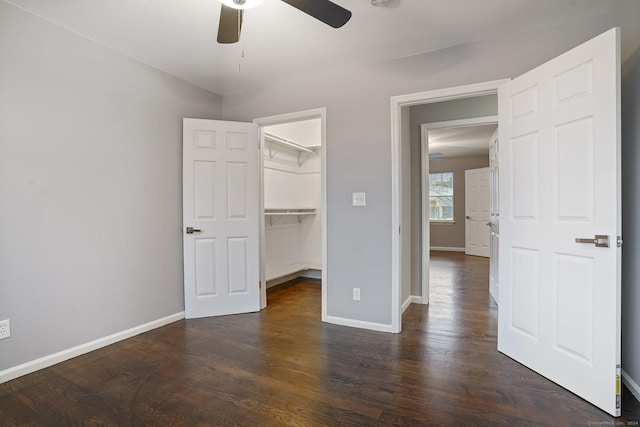 unfurnished bedroom with ceiling fan, dark hardwood / wood-style floors, a walk in closet, and a closet