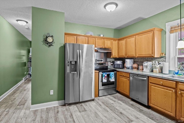 kitchen featuring sink, a textured ceiling, decorative light fixtures, light hardwood / wood-style floors, and stainless steel appliances