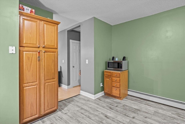 kitchen featuring a textured ceiling, light hardwood / wood-style floors, and a baseboard heating unit