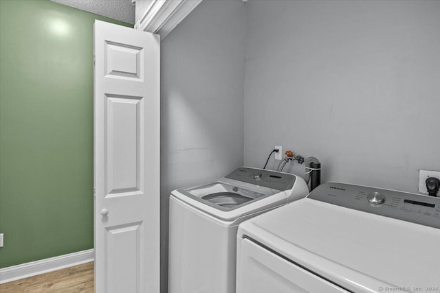 laundry room with washer and dryer, light wood-type flooring, and a textured ceiling