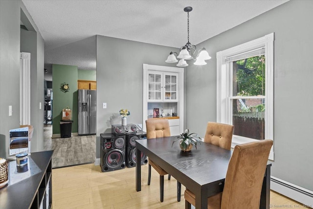 dining area with a chandelier, a textured ceiling, light wood-type flooring, and baseboard heating