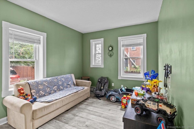 sitting room featuring baseboard heating, a wealth of natural light, light hardwood / wood-style floors, and a textured ceiling