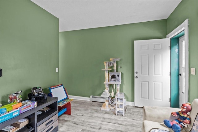 game room featuring baseboard heating and light wood-type flooring