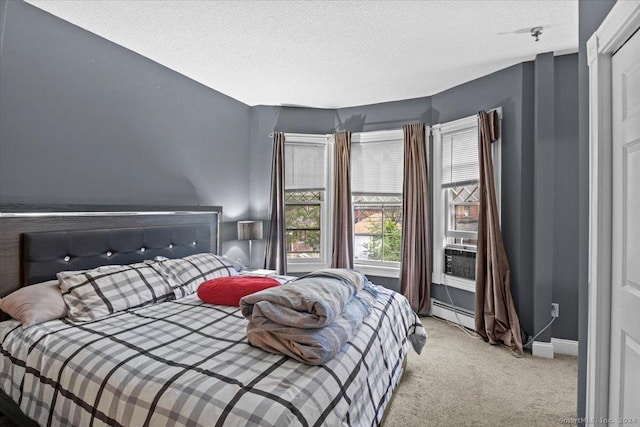 bedroom featuring light colored carpet, baseboard heating, and a textured ceiling