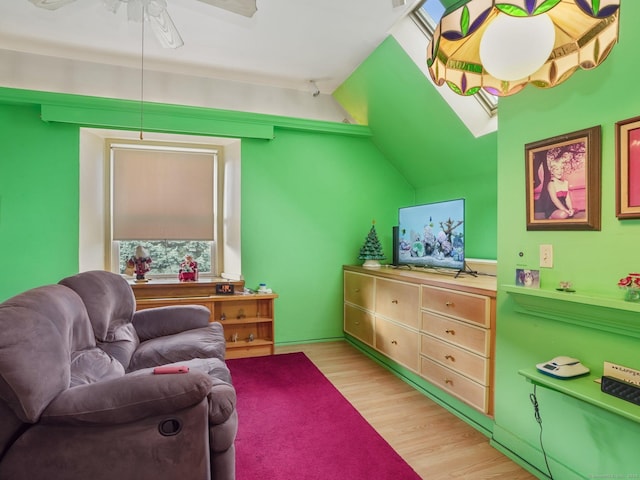 sitting room with light hardwood / wood-style floors, ceiling fan, and vaulted ceiling with skylight