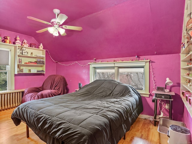 bedroom with hardwood / wood-style flooring, vaulted ceiling, multiple windows, and ceiling fan