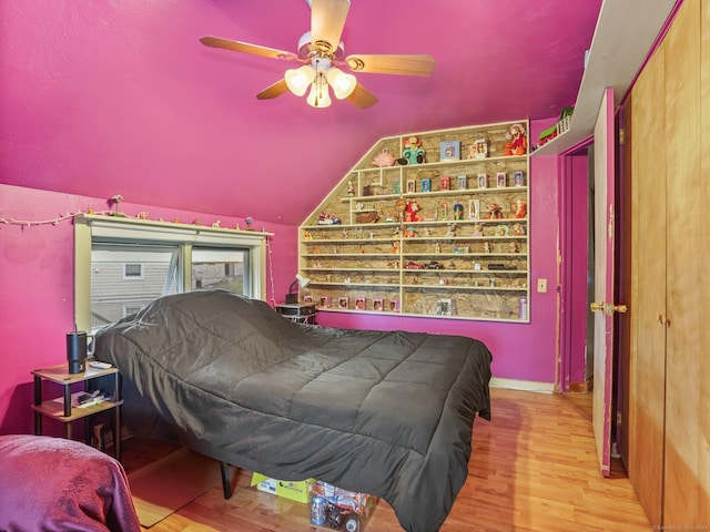 bedroom with ceiling fan, light hardwood / wood-style flooring, and vaulted ceiling