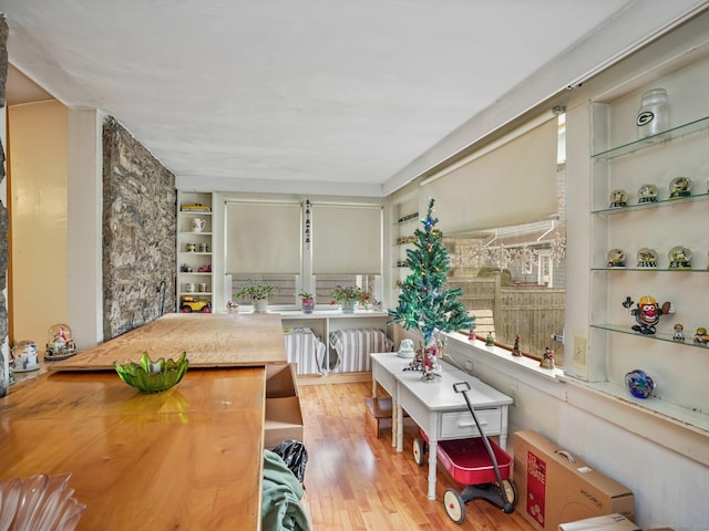 dining room with built in shelves, radiator heating unit, and light hardwood / wood-style flooring