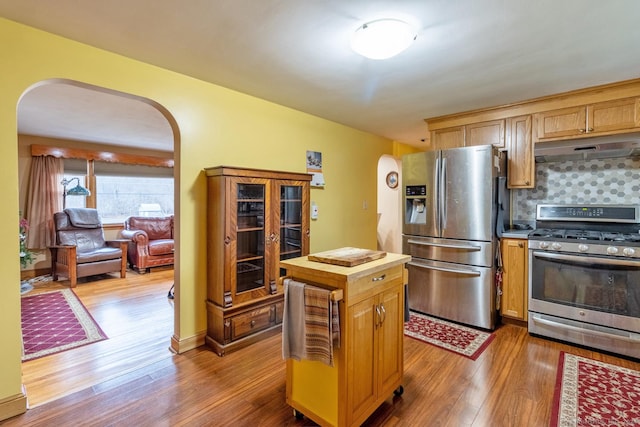 kitchen with dark wood-type flooring, appliances with stainless steel finishes, and tasteful backsplash