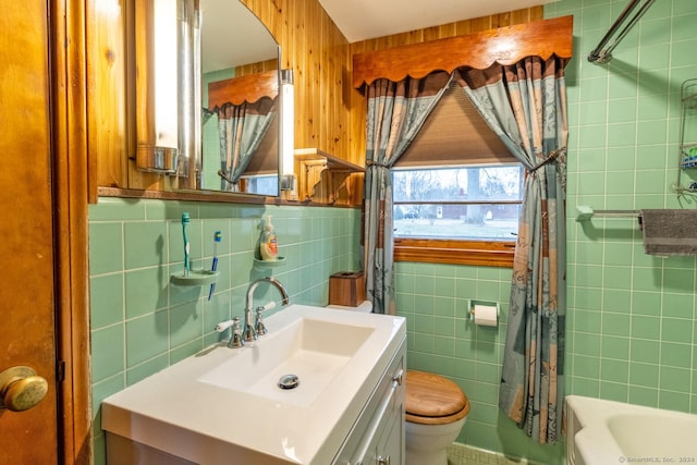 full bathroom with tile walls, toilet, vanity, and shower / bathtub combination with curtain