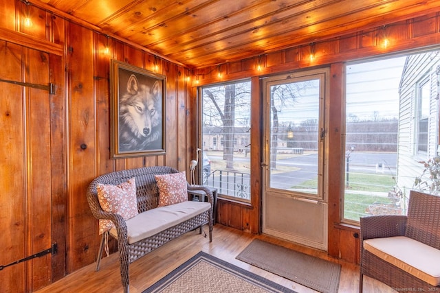 doorway to outside featuring light hardwood / wood-style floors, a wealth of natural light, and wooden walls