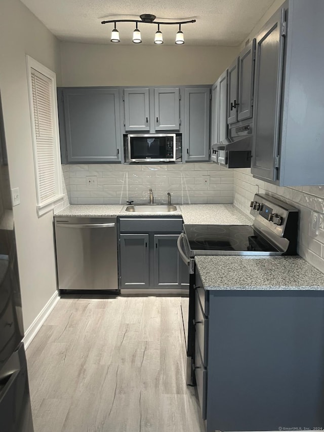 kitchen with backsplash, gray cabinetry, stainless steel appliances, extractor fan, and sink