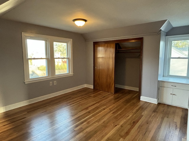 unfurnished bedroom with a closet, dark hardwood / wood-style flooring, and vaulted ceiling