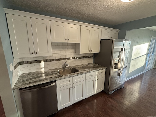 kitchen featuring sink, backsplash, a textured ceiling, white cabinets, and appliances with stainless steel finishes