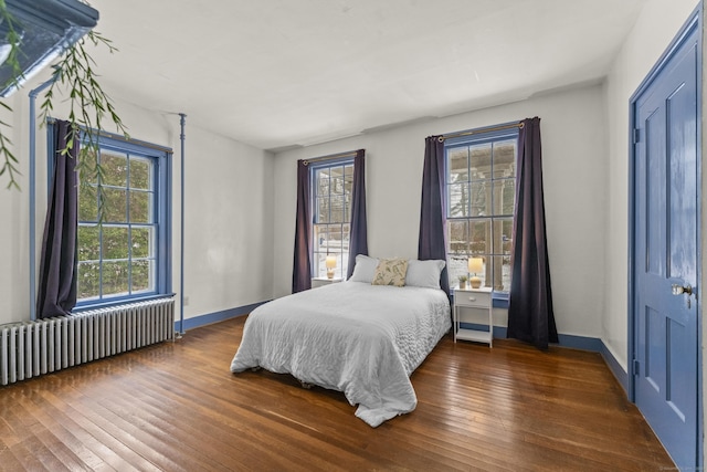 bedroom featuring radiator, dark hardwood / wood-style flooring, and multiple windows