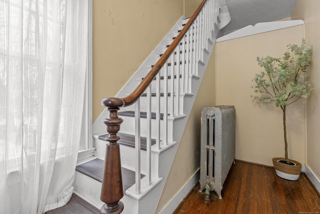 stairs featuring hardwood / wood-style floors and radiator heating unit