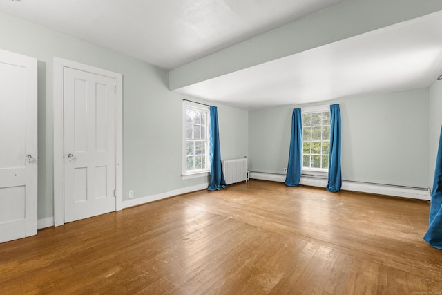 spare room featuring radiator heating unit and hardwood / wood-style flooring