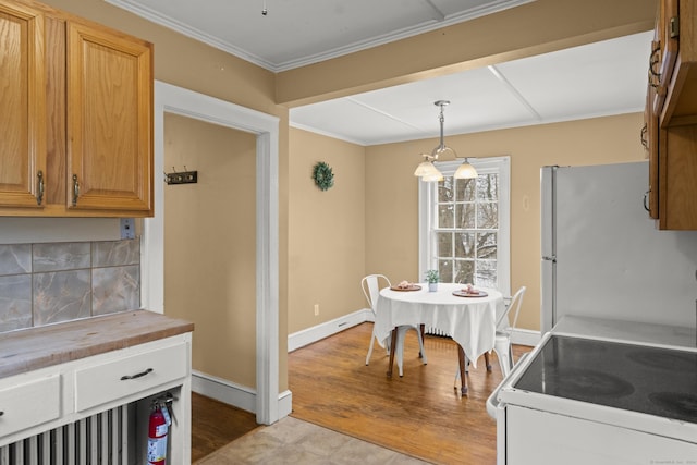 kitchen featuring light hardwood / wood-style flooring, crown molding, white appliances, decorative light fixtures, and decorative backsplash