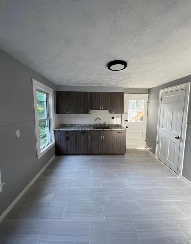 kitchen featuring dark brown cabinets, sink, and a textured ceiling