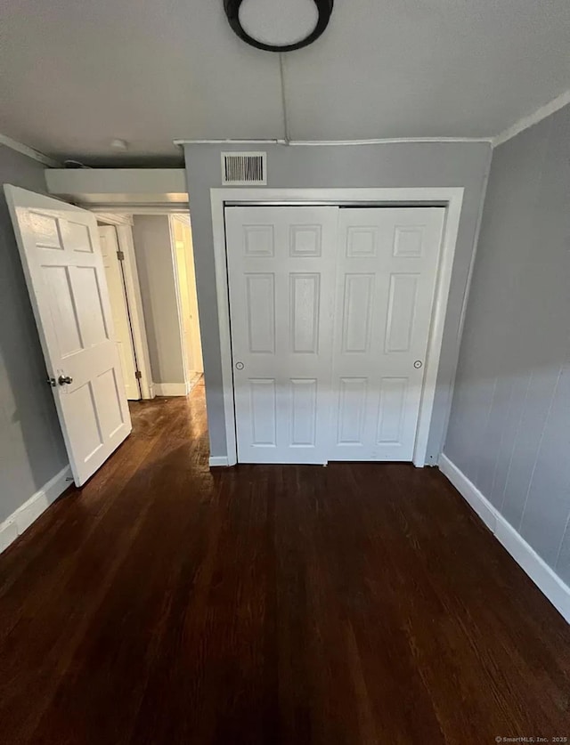 interior space featuring dark hardwood / wood-style flooring, ornamental molding, and a closet