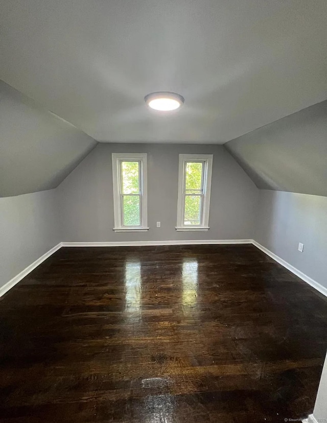 additional living space with vaulted ceiling and dark hardwood / wood-style floors