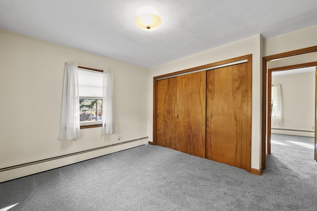 unfurnished bedroom with carpet, baseboard heating, and a closet