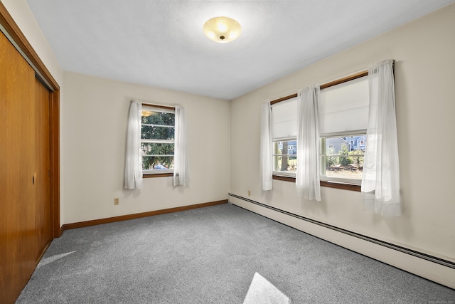 unfurnished bedroom featuring carpet flooring, a closet, and a baseboard heating unit