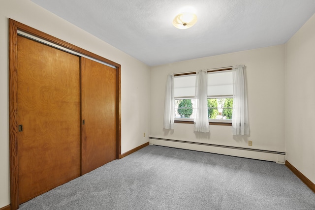 unfurnished bedroom featuring carpet, a baseboard radiator, and a closet