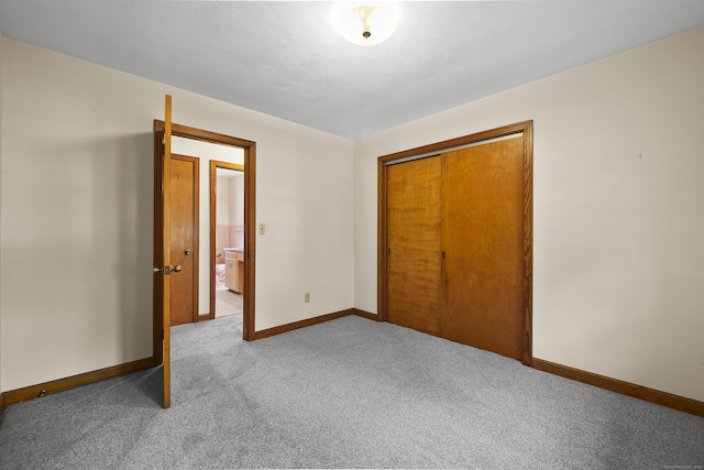 unfurnished bedroom featuring light carpet, a closet, and a textured ceiling