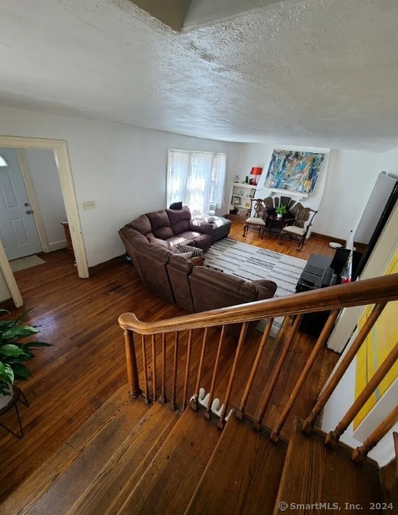 stairway with hardwood / wood-style floors and a textured ceiling