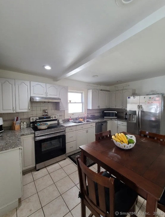 kitchen featuring white cabinets, light tile patterned floors, appliances with stainless steel finishes, and tasteful backsplash