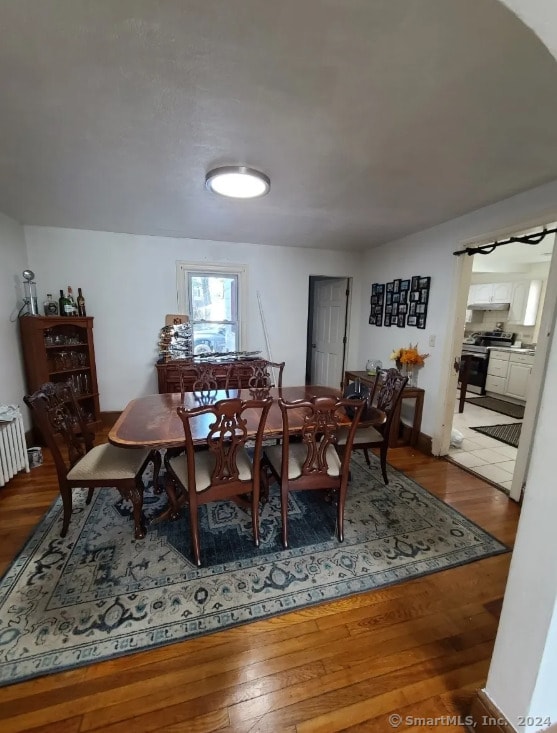 dining room with hardwood / wood-style floors and radiator heating unit