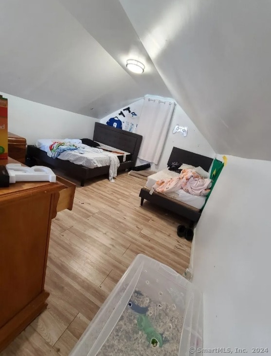 bedroom featuring light hardwood / wood-style floors and lofted ceiling