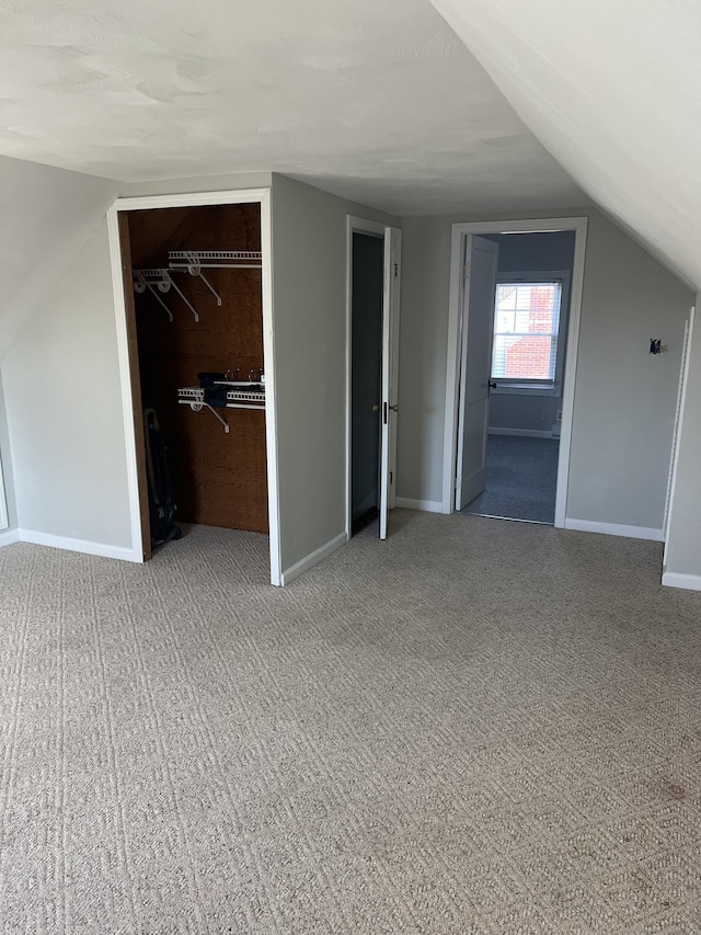 unfurnished bedroom featuring carpet flooring, vaulted ceiling, a spacious closet, and a closet