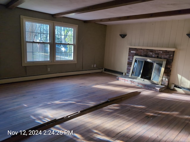 unfurnished living room with wood walls, a fireplace, baseboard heating, beamed ceiling, and wood-type flooring