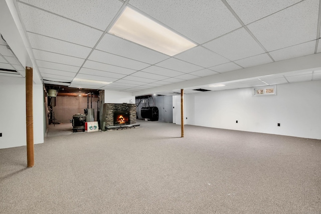 basement with carpet flooring, a paneled ceiling, and water heater