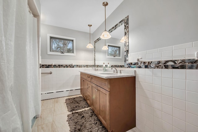 bathroom with baseboard heating, tile patterned floors, vanity, and tile walls