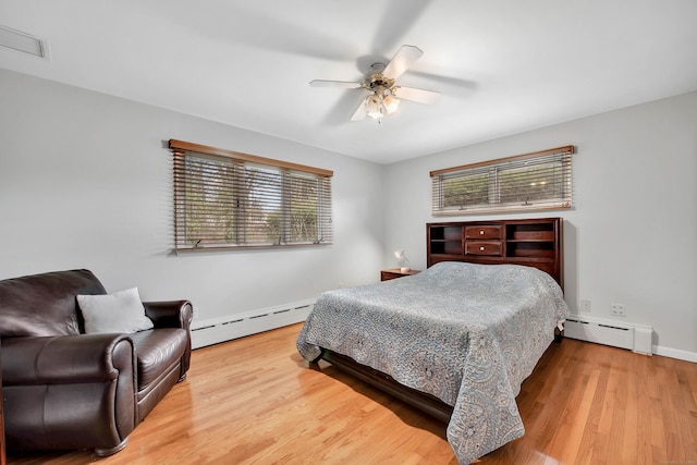 bedroom featuring multiple windows, ceiling fan, and a baseboard heating unit