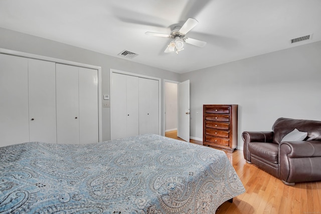 bedroom featuring light wood-type flooring, ceiling fan, and multiple closets